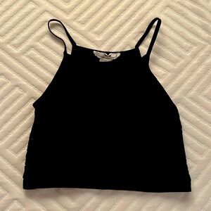 A cropped black shirt with a black flower design and spaghetti straps